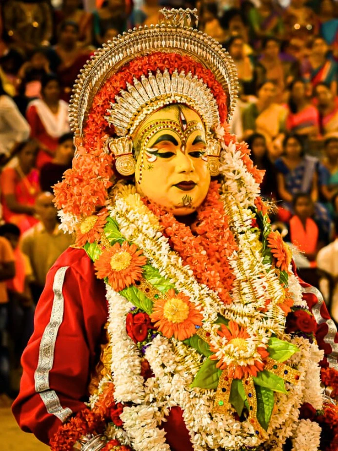 A Bhoota Kola performer in silver crown and flower garlands