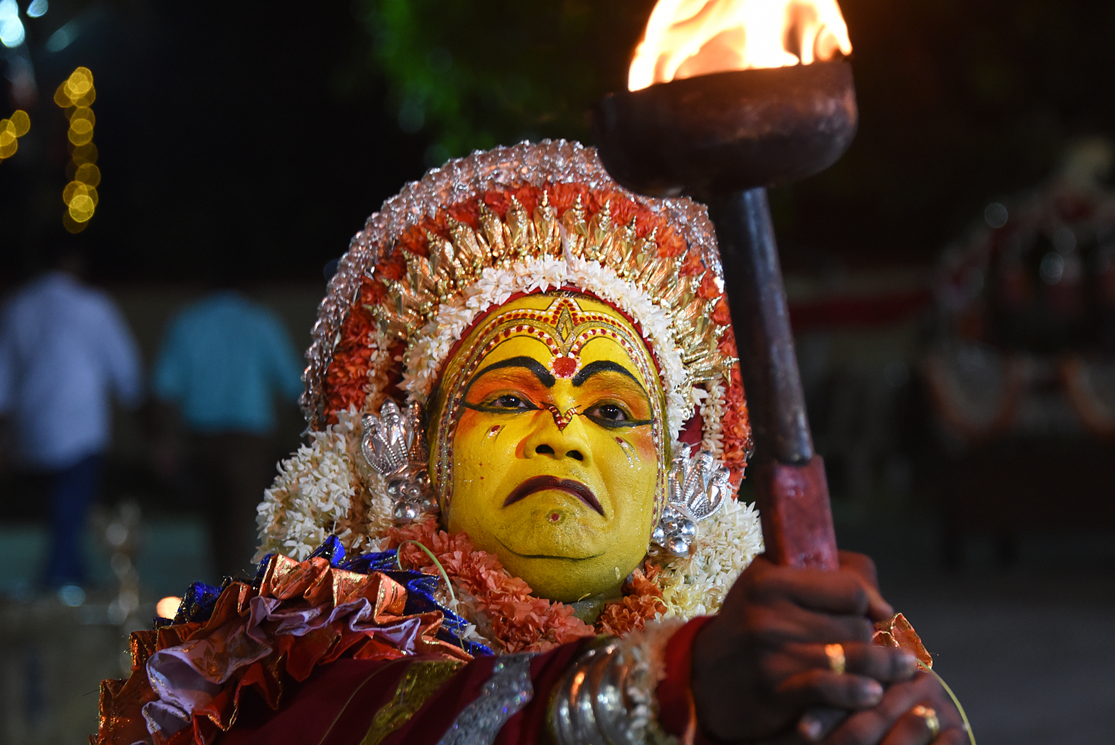 A Bhoota Kola performer surrounded by torchlight during the night ritual