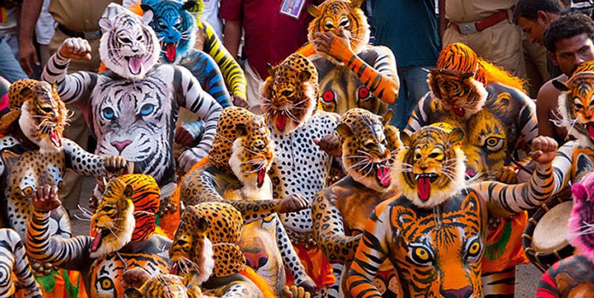 A dense, vivid crowd of Huli Vesha performers wearing tiger and leopard masks with bright body paint, mid-dance