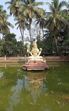 A Shiva statue set in the green temple pond at Kundeshwara