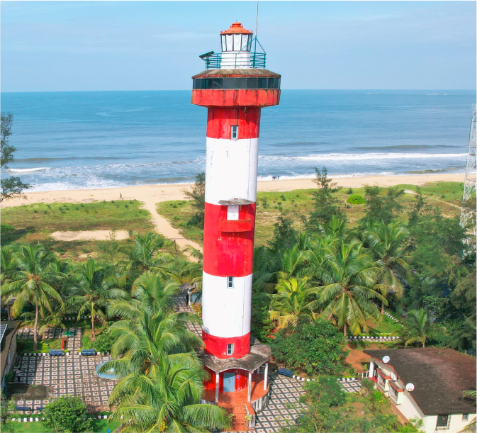 The red-and-white Kundapura lighthouse above the beach