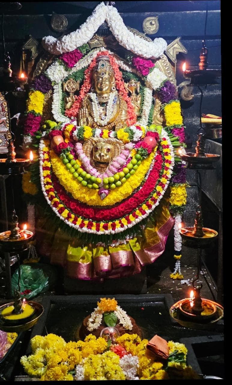 The golden idol of Brahmi Durgaparameshwari at Kamalashile, garlanded with marigolds above a lion face-emblem
