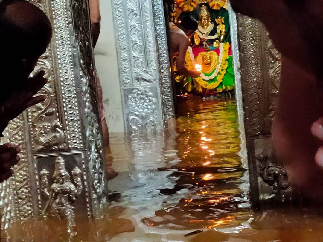 Monsoon floodwaters of the Kubja river fill the silver-framed sanctum at Kamalashile, reaching the feet of the garlanded Goddess as a priest performs aarti