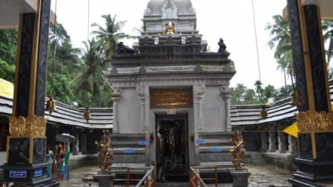 The grey stone gopura and bell-lined courtyard of the Sri Shankaranarayana Temple after rain